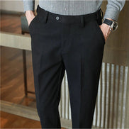 A person wearing slim black trousers with a matching black belt, paired with a gray button-up shirt. 
