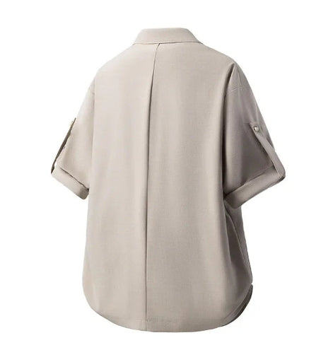A light beige short-sleeve button-up shirt shown from the back, featuring a central seam and sleeve button details, set against a plain white background.