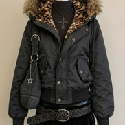 A black puffer jacket with a brown and black leopard-print faux fur hood lining, displayed on a mannequin with a black skirt, braided belt, and a dark denim crossbody bag.