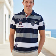 A short-sleeve polo shirt with horizontal navy blue, white, and heather gray stripes, featuring multiple decorative patches and a collar, shown 