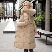 Woman wearing a beige puffer coat with fur hood on a city street.