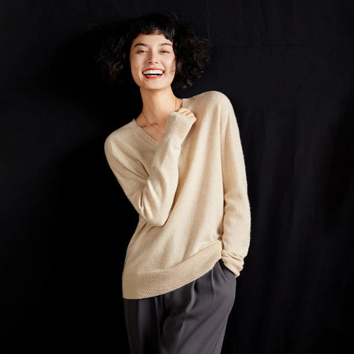 Woman wearing a beige sweater against a black background