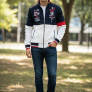 A men's zip-up track jacket with a color-blocked design in navy blue, white, and red. The jacket features graphic prints with 'SHARK' 