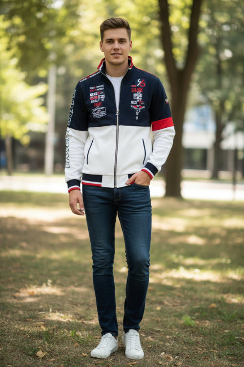 A men's zip-up track jacket with a color-blocked design in navy blue, white, and red. The jacket features graphic prints with 'SHARK' 