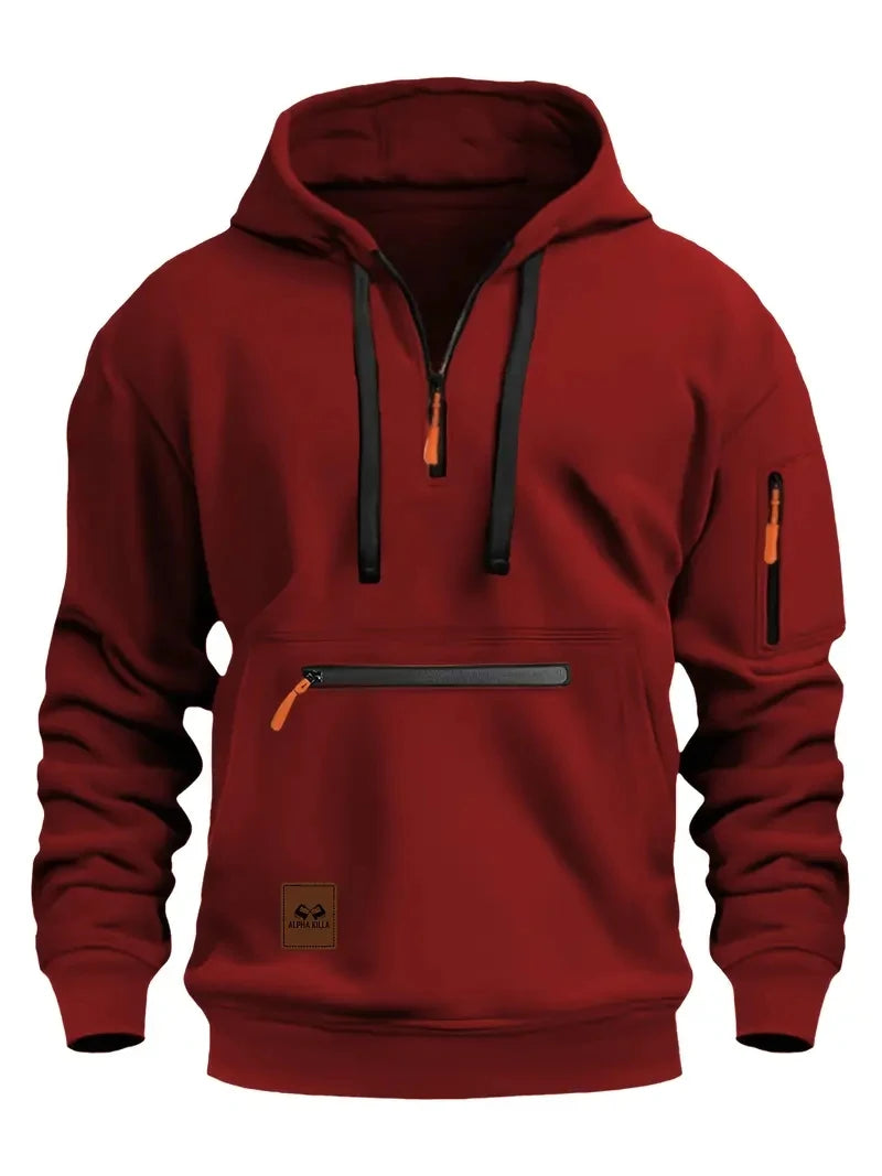 A dark red pullover hoodie with black drawstrings, a black horizontal chest zipper, and orange zipper pulls, shown on a plain white background.