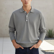 Person wearing a gray long-sleeve polo shirt against a plain background