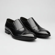 Black dress shoes worn with black pants on a gray background