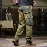 Rear-angle view of a model wearing faded olive-brown cargo jeans with large flap thigh pockets and stitched back pockets, paired with brown boots.