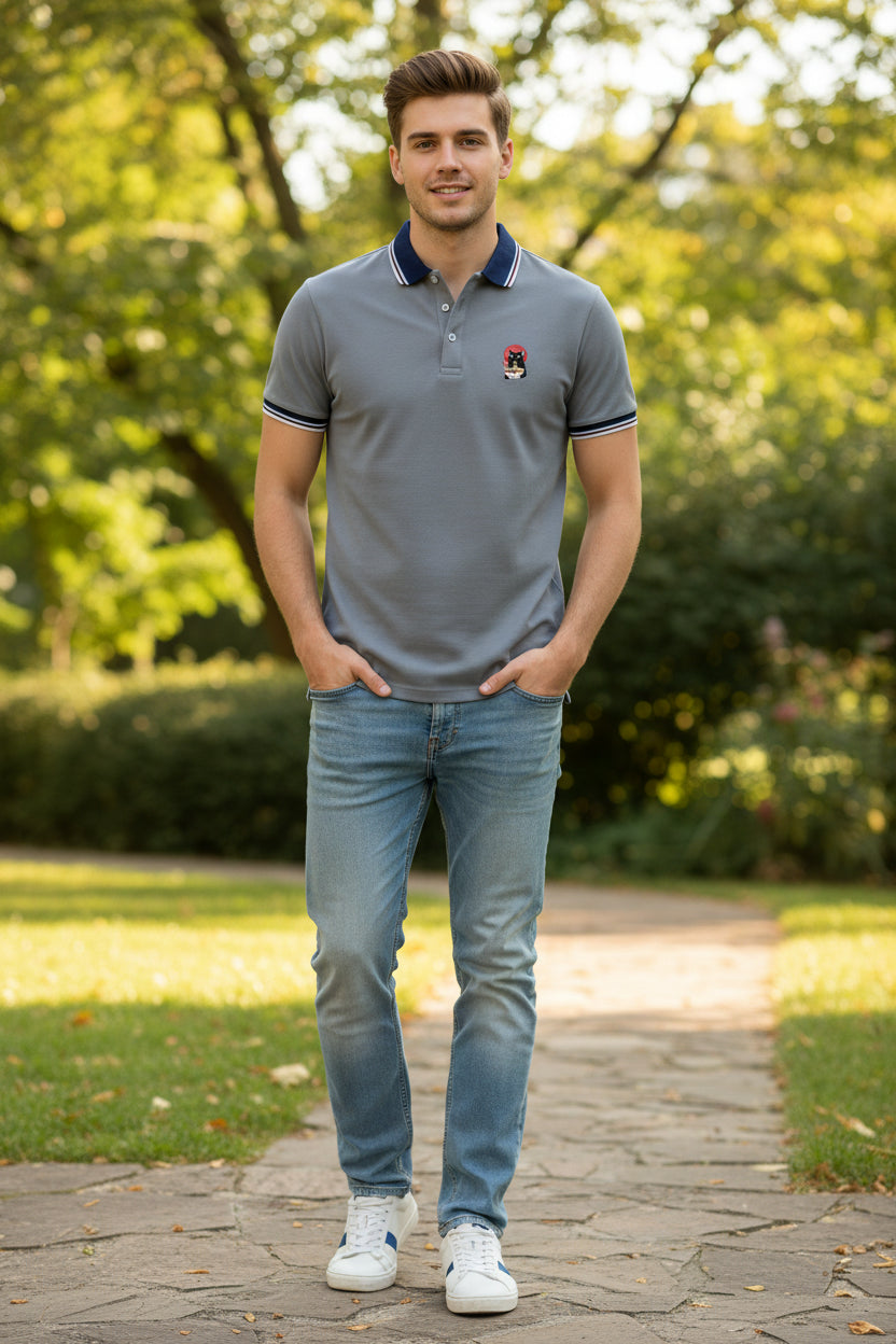 A men's short-sleeve polo shirt in gray, featuring a navy blue and white striped collar, navy and white striped sleeve cuffs, and a small cartoon dog graphic on the left chest.