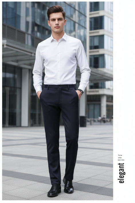 A man wearing slim-fit dark charcoal gray dress pants, styled with a white long-sleeve shirt and black leather dress shoes, standing against a dark gray studio background.