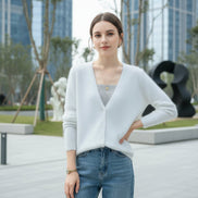 A woman wearing a fuzzy white V-neck cardigan over a ribbed gray top, with blue 