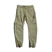 Light khaki cargo pants laid flat against a white background, showing angled thigh pockets, buttoned flap pockets, side straps, and gathered ankle cuffs.
