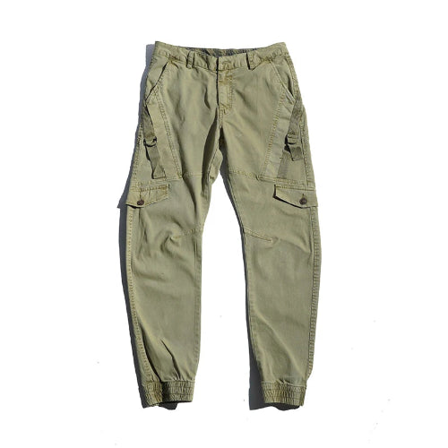 Light khaki cargo pants laid flat against a white background, showing angled thigh pockets, buttoned flap pockets, side straps, and gathered ankle cuffs.
