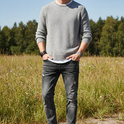 Black leather shoes worn with rolled-up jeans on a gray background