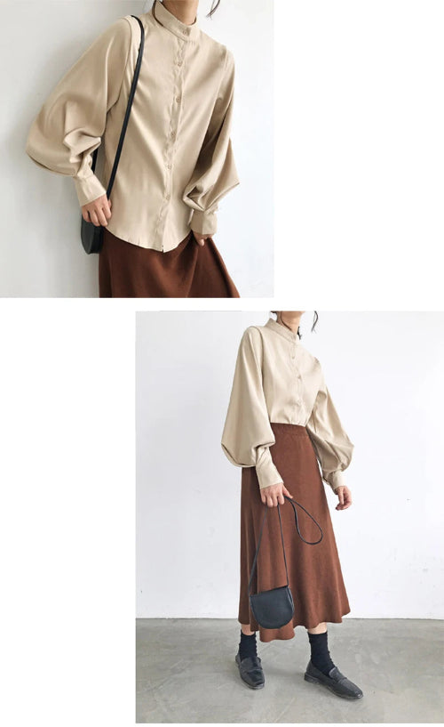 Person wearing a beige blouse and brown skirt with a black handbag against a white background