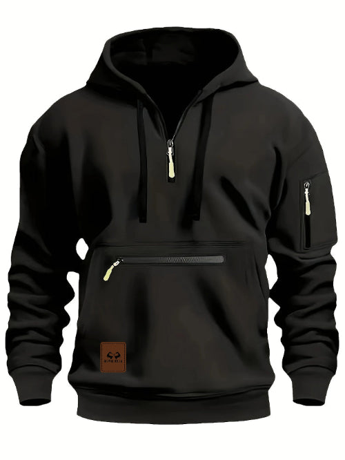 A black pullover hoodie with a half-zip neckline, a front kangaroo pocket with a horizontal zip, a sleeve zip pocket, and a brown brand patch on the lower left front.