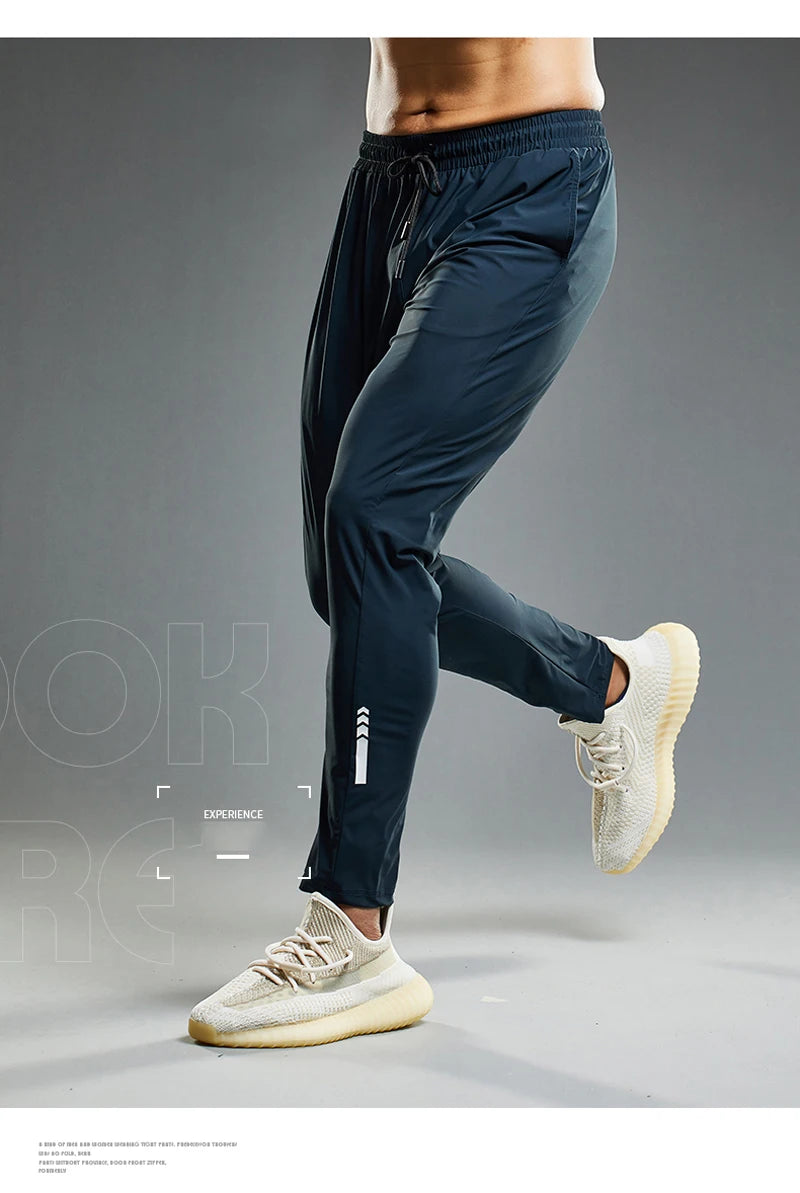Person wearing navy jogger pants and white sneakers on a gray background