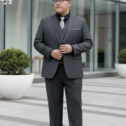 Man wearing a gray suit with a vest and tie, standing in front of a glass door.