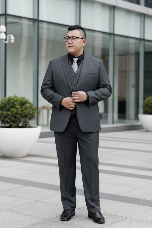 Man wearing a gray suit with a vest and tie, standing in front of a glass door.