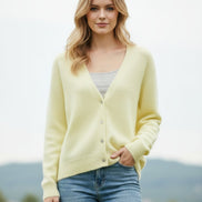 A person wearing a pale pastel yellow fuzzy V-neck cardigan over a gray ribbed top 