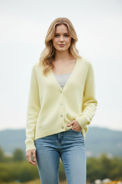 A person wearing a pale pastel yellow fuzzy V-neck cardigan over a gray ribbed top 