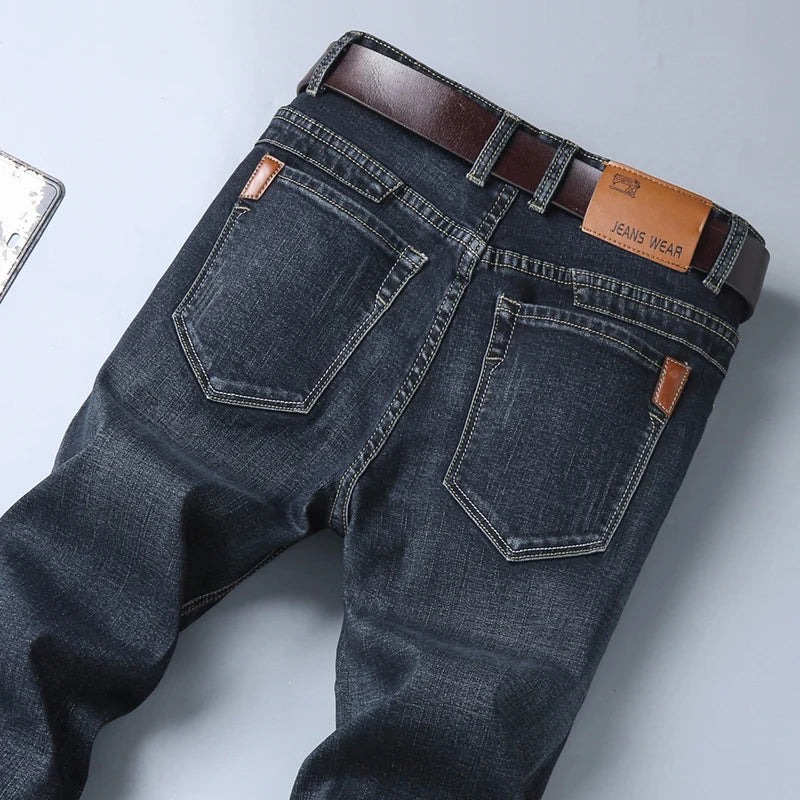 Dark blue jeans with a brown belt on a light gray background