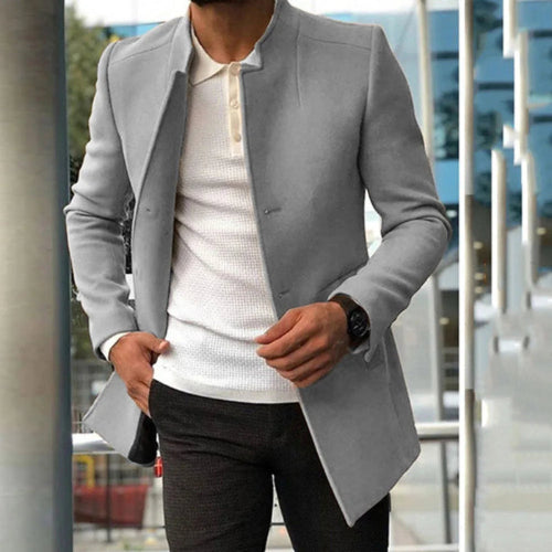 Person wearing a gray blazer over a white shirt with a blurred cityscape background