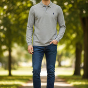 Gray long-sleeve polo shirt with a brand logo on a hanger in a clothing store.