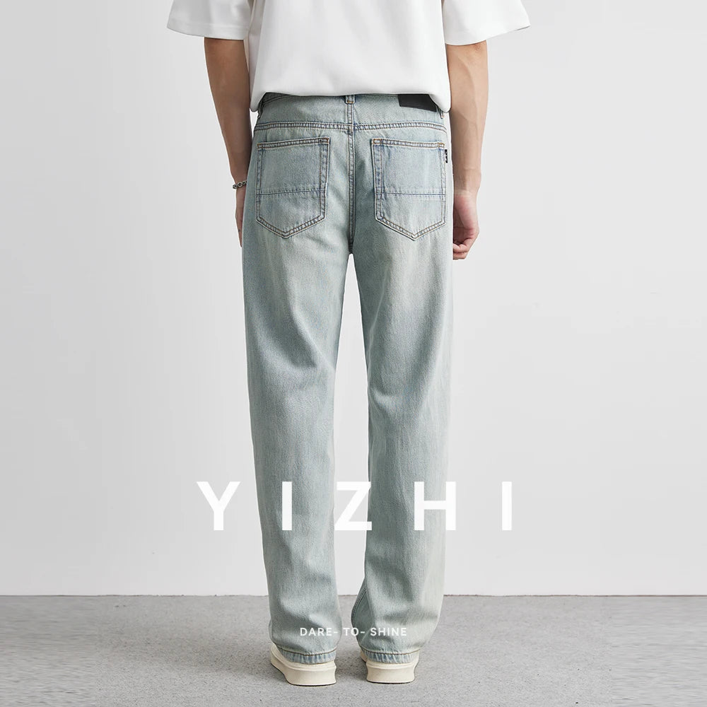 Person wearing light blue jeans with 'YIZHI' branding on a plain background