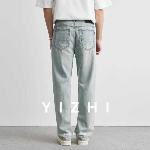 Person wearing light blue jeans with 'YIZHI' branding on a plain background