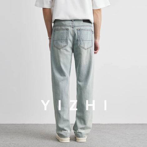 Person wearing light blue jeans with 'YIZHI' branding on a plain background