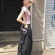 Woman posing sideways in dark-wash loose-fit jeans with contrast stitching, her hand in the back pocket featuring a pink heart outline.
