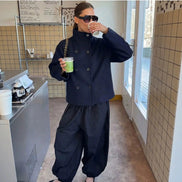 Woman wearing a navy double-breasted short coat with black trousers in a café