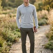 A light gray heather knit polo sweater hanging on a wooden hanger against a dark gray gradient background.