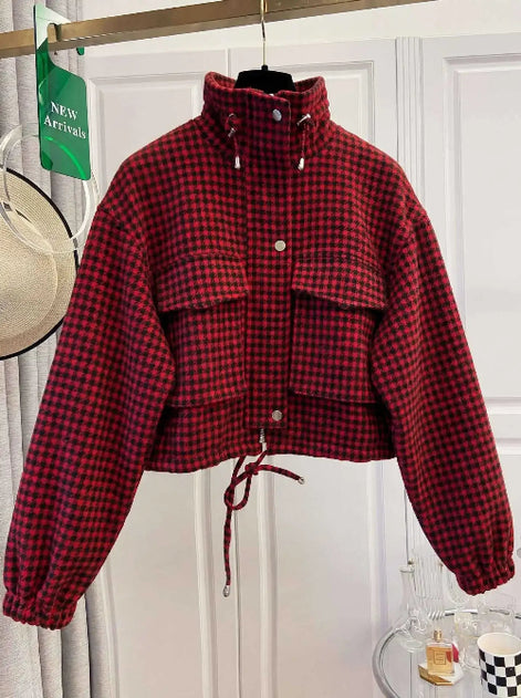 Red and black checked utility jacket on a hanger, showing a raised drawcord collar, chest flap pockets, front snap buttons, elasticated cuffs and a drawcord hem