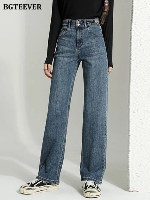 A person wearing high-waisted, wide-leg blue denim jeans with a black long-sleeve top and black-and-white sneakers