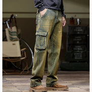 Side-angle view of a model wearing faded olive-brown cargo pants with a large flap thigh pocket and one hand in a side pocket, paired with brown boots.