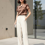 Brown satin blouse on a hanger against a beige background