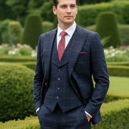 Man wearing a navy checkered suit with a red tie in a garden setting