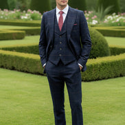 Man wearing a navy checkered suit with a red tie in a garden setting
