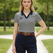 A woman wearing a short-sleeve black and white horizontally striped polo shirt with a solid black collar. The shirt features a small black oval patch on the left chest with the white text '1910'.
