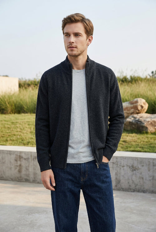 A dark charcoal gray knit zip-up sweater with a mock neck collar, hanging on a wooden hanger against a light gray background. 