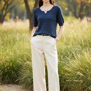 Woman wearing a blue textured sweater with a blurred outdoor background