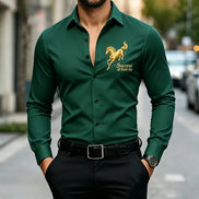 A man wearing a dark green long-sleeve button-up shirt with a gold embroidered horse and the words 'Success at first try' on the left chest, 