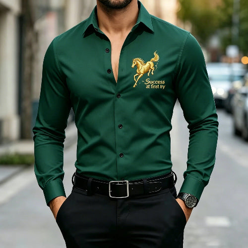 A man wearing a dark green long-sleeve button-up shirt with a gold embroidered horse and the words 'Success at first try' on the left chest, 