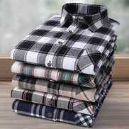 Stack of folded plaid shirts on a wooden surface with a blurred background