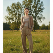 A person wearing a fuzzy taupe-beige cardigan over a ribbed top and beige pants, 