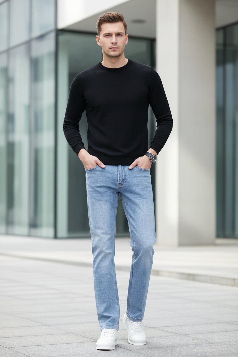 Person wearing light blue jeans and white sneakers on a gray background