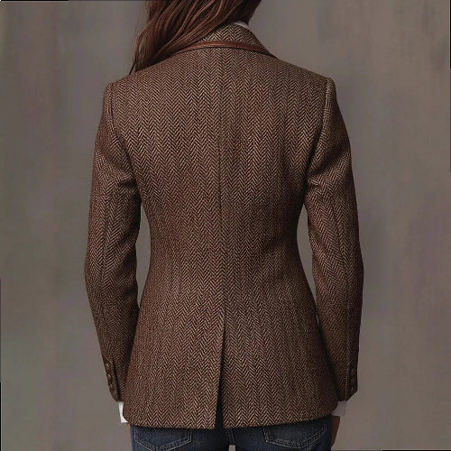 Back view of a woman wearing a brown herringbone-pattern jacket with a shaped waist, center back vent and contrast collar trim