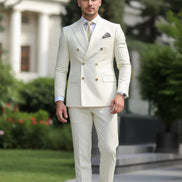Man wearing a cream double-breasted suit with a blurred green background